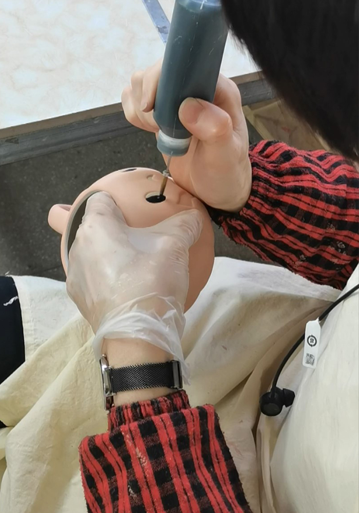 An artisan hand-painting fine details on a pig-shaped ceramic mug using a precision pen tool, wearing gloves in a pottery workshop